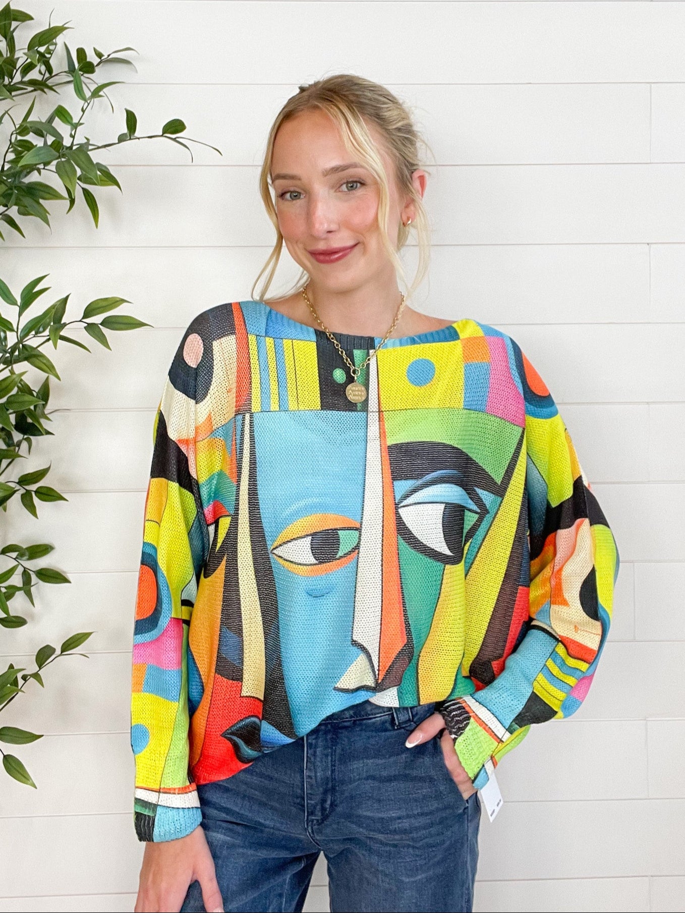 Woman wearing a colorful abstract-patterned sweater against a white wooden panel background