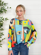 Woman wearing a colorful abstract-patterned sweater against a white wooden panel background
