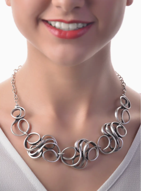 Silver necklace worn by a person with a plain background