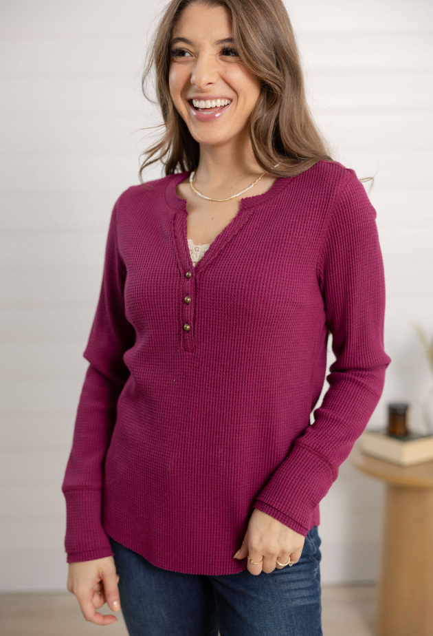 Woman wearing a purple long-sleeve shirt with buttons, standing indoors.