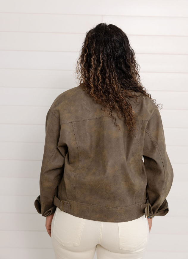 Person wearing a brown leather jacket from behind against a white wall
