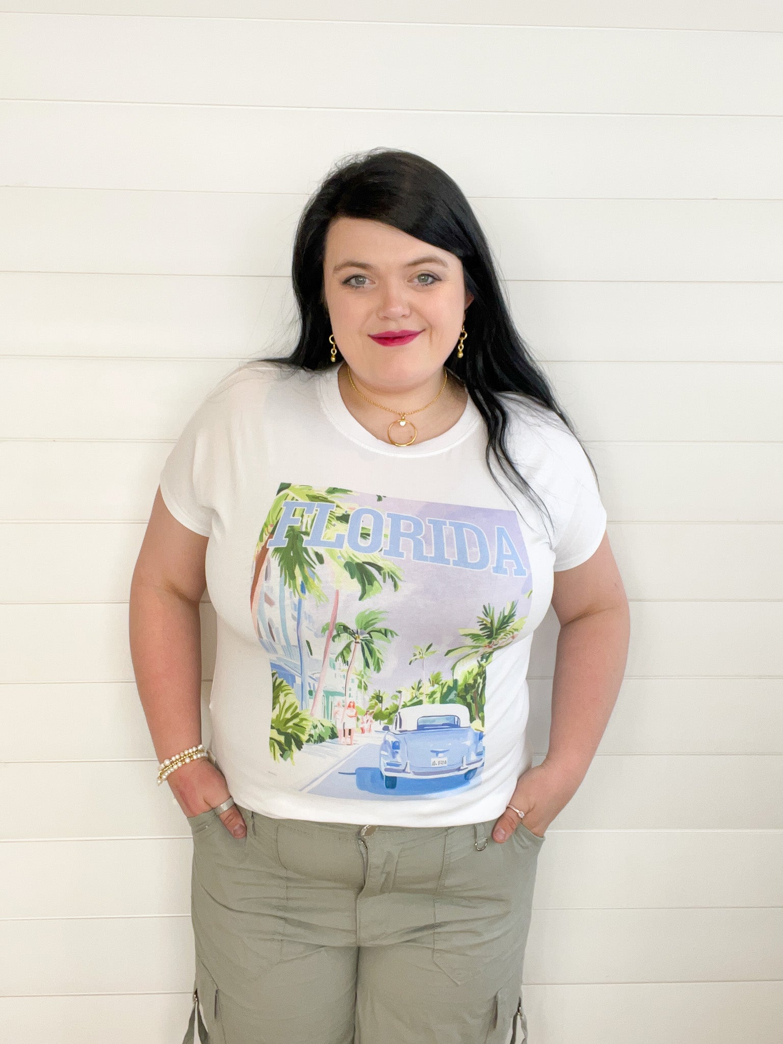women's fashion tee featuring a graphic of a road lined with walk trees, ladies walking down the side walk, and a vintage car, with the word "Florida" across the top