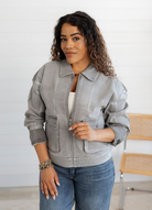 Woman wearing a gray jacket and blue jeans indoors