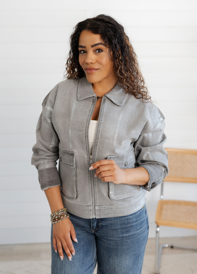 Woman wearing a gray jacket and blue jeans indoors